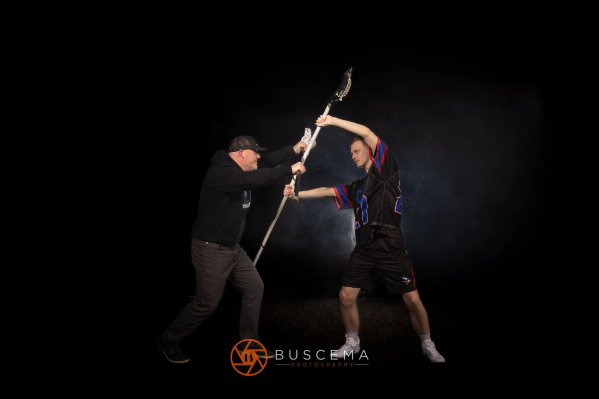 Two athletes in competitive stance with torch during JPB event against dark background.