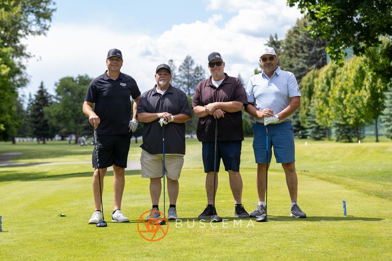 A foursome posing on the tee box under blue skies