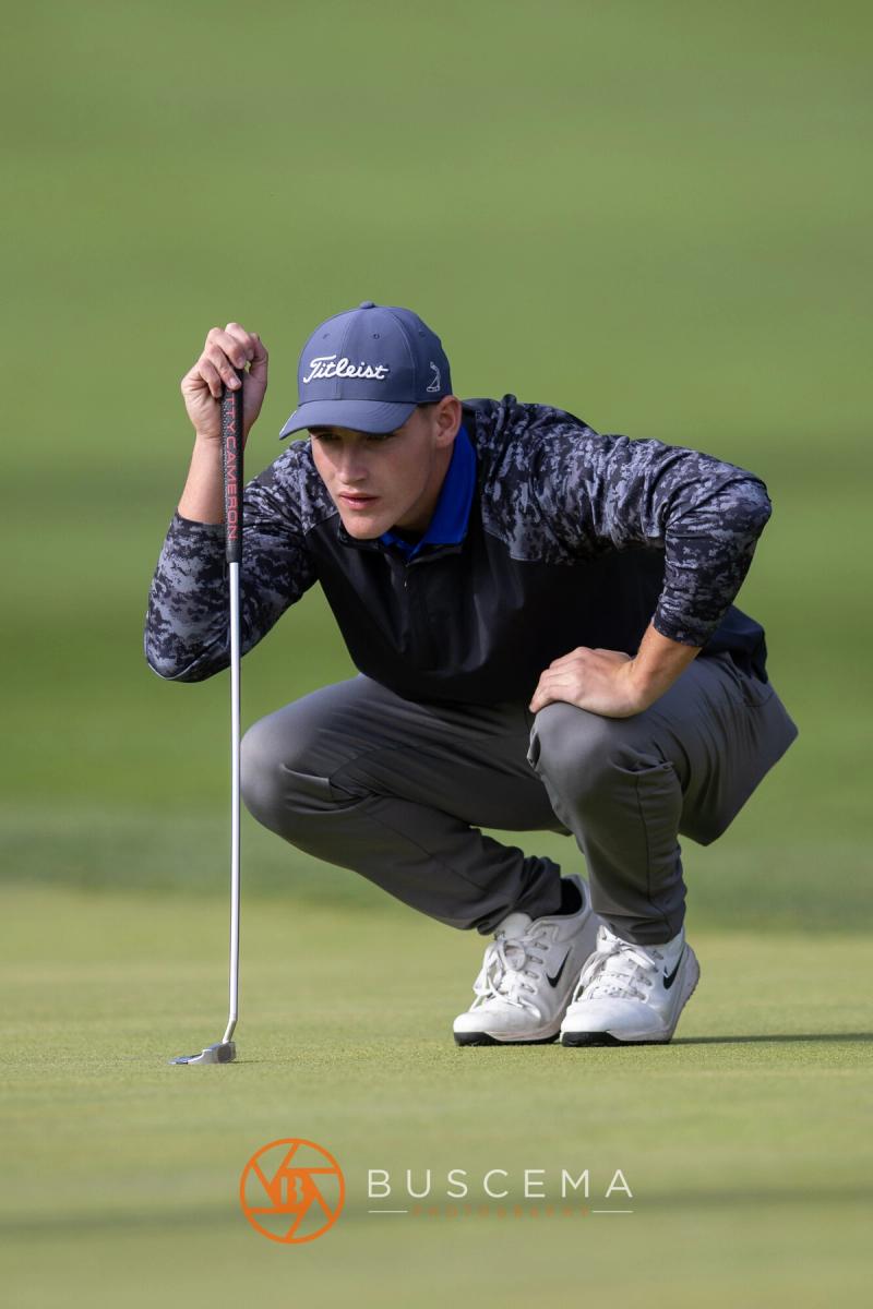 Boys golfer squatting behind his ball to read a putt at the 6A state golf championships at Avondale Golf Club