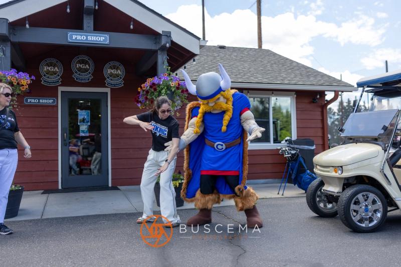 A golfer dancing with the Viking mascot outside the pro shop