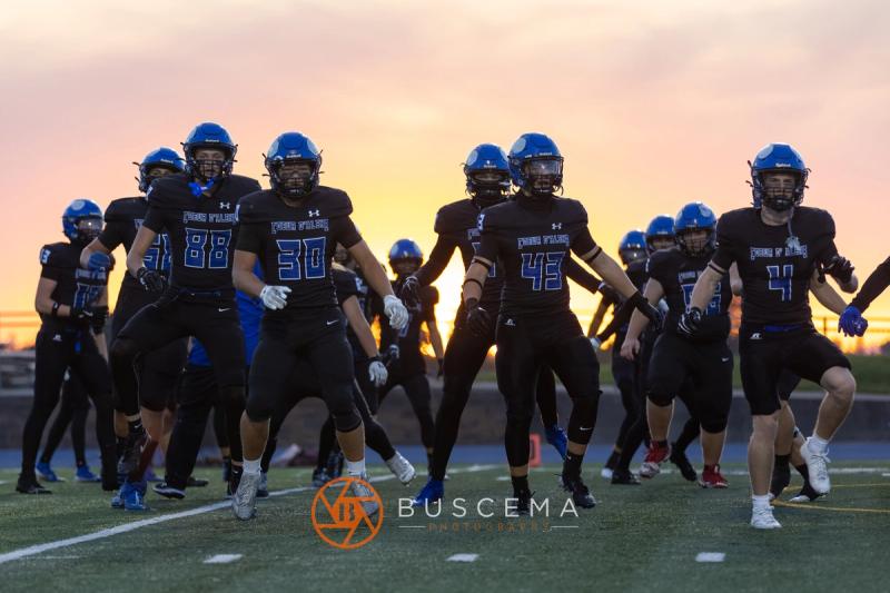 Coeur d'Alene players gathered on the field against an orange sunset