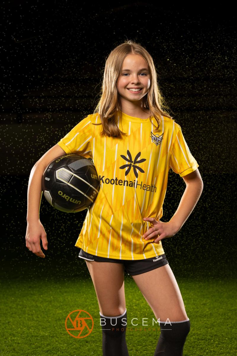 Smiling Sting 13G Academy player holding a ball on her hip