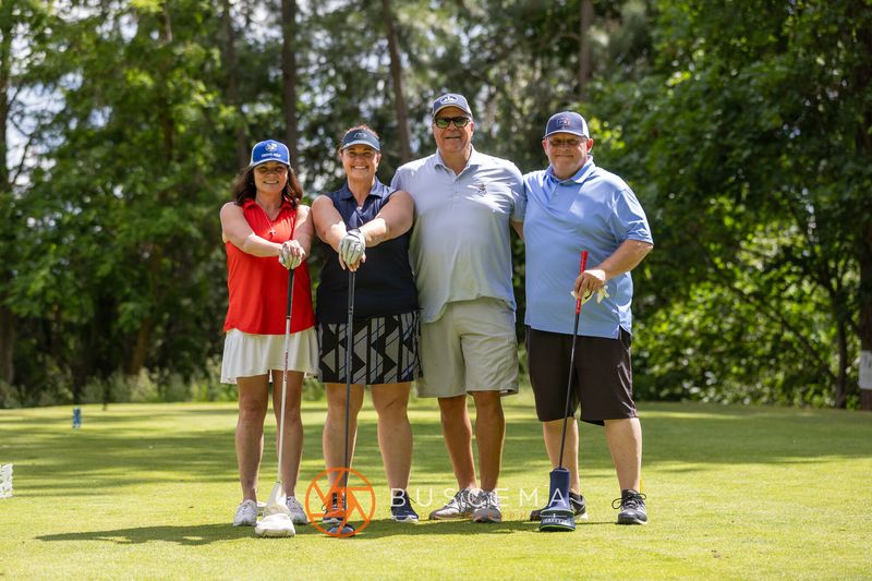 A foursome posing together with their clubs on the tee box