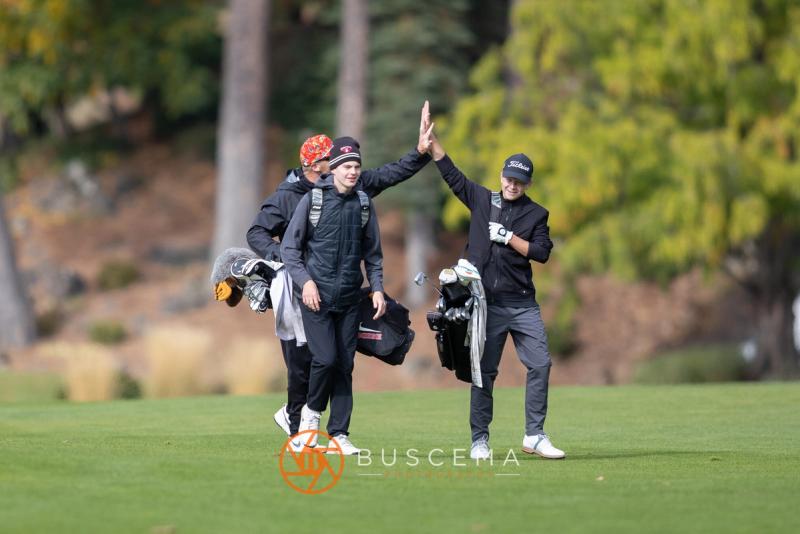 Golfers trading a high five as they walk down the fairway at the 6A state golf championships at Avondale Golf Club