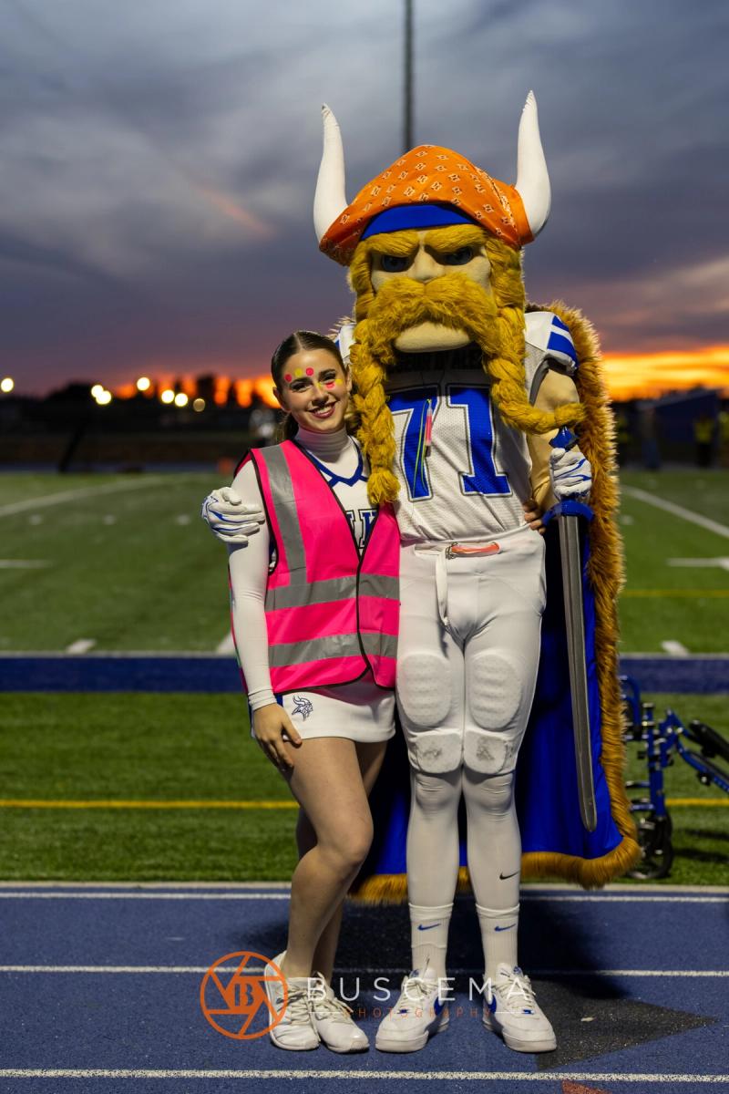 A Coeur d'Alene cheerleader with the Viking mascot at sunset