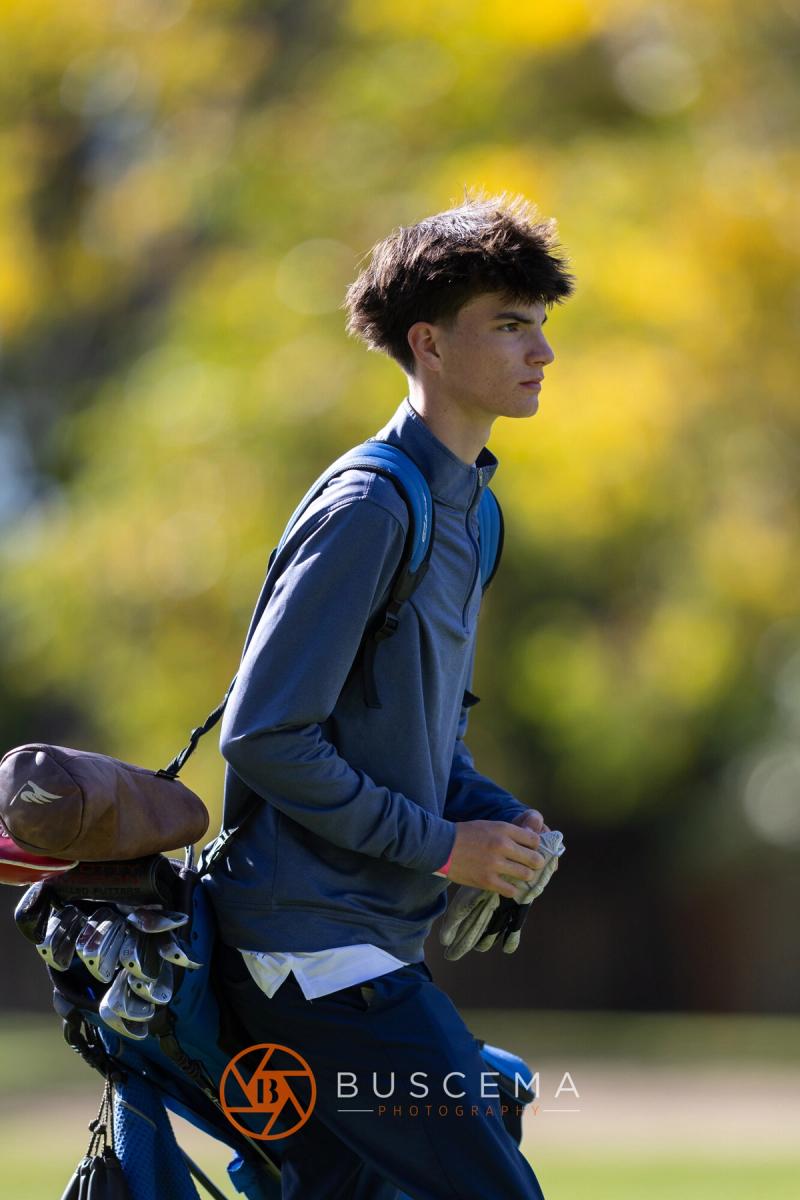 Boys golfer walking to the next hole with fall leaves behind him at the 6A state golf championships at Avondale Golf Club