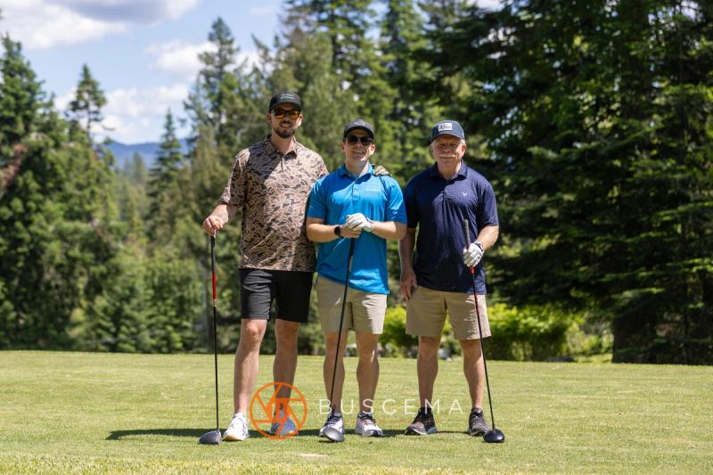 Three golfers posing with their drivers on a tee box