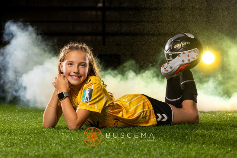 Smiling Sting 13G Academy player lying on the turf with her chin in her hands
