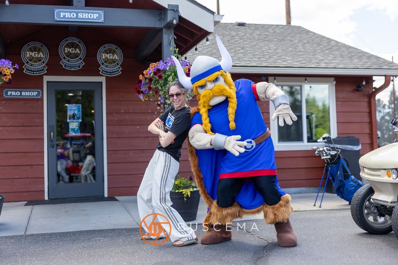 A golfer and the Viking mascot mid dance in front of the pro shop