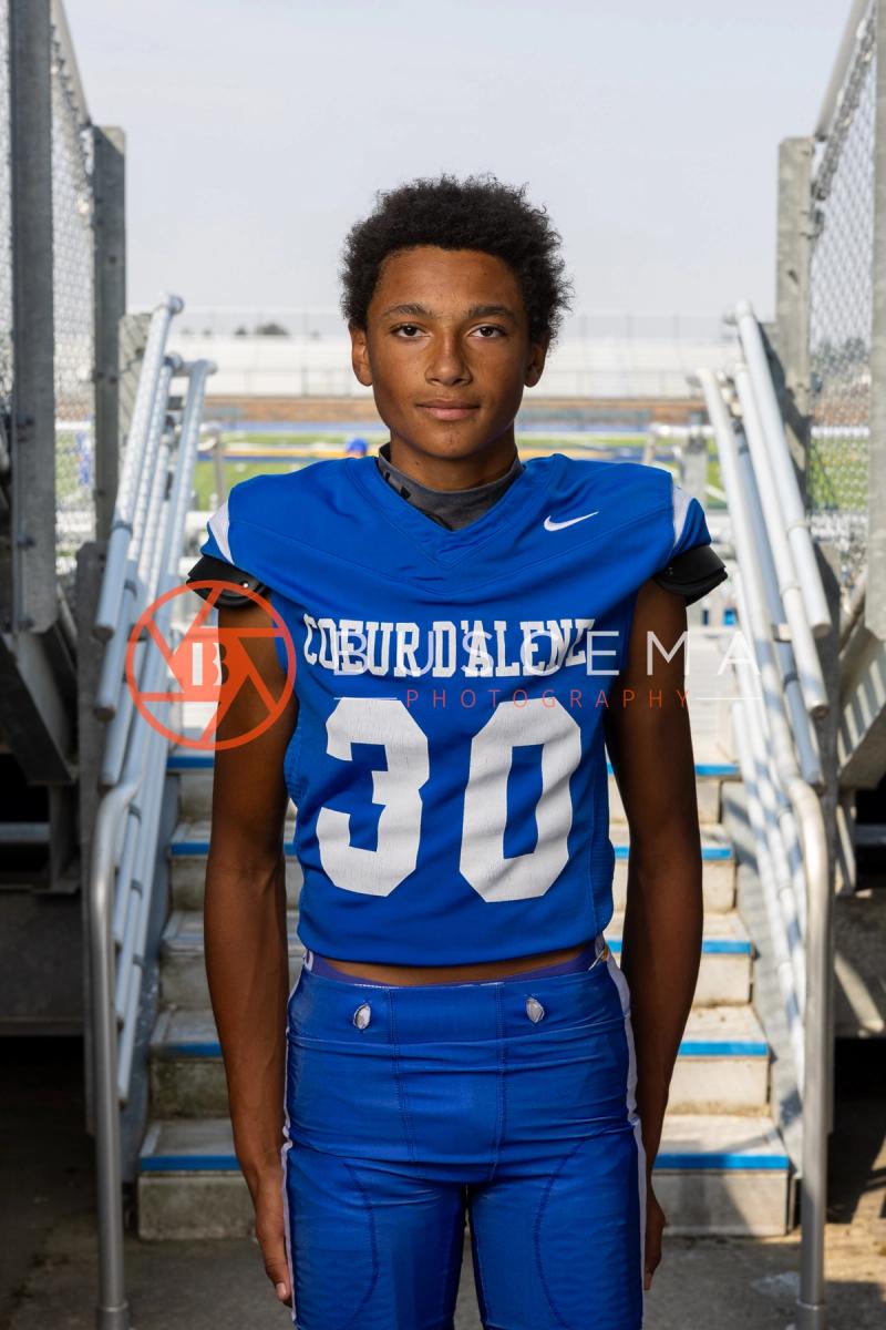 Coeur d'Alene High School football player in a number 30 jersey on the bleacher steps