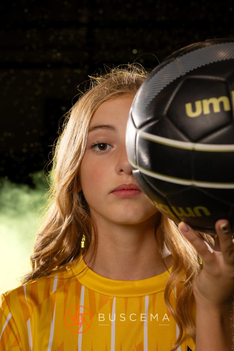 Sting 13G Academy player peeking out from behind a soccer ball at media day