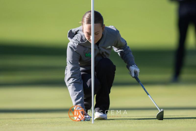 Girls golfer crouched by the flagstick reading her line at the 6A state golf championships at Avondale Golf Club