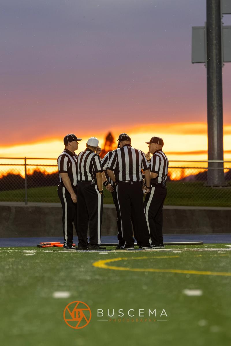 Officials conferring at midfield at Viking Field as the sun sets