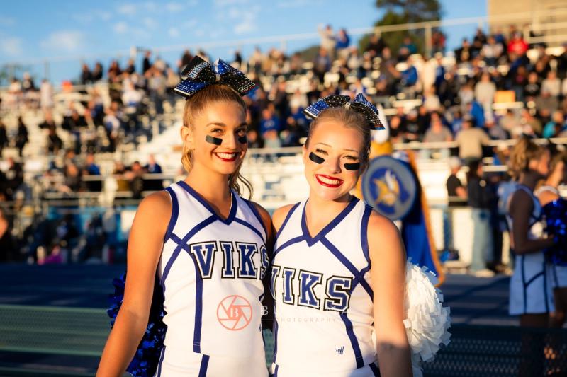 Two Coeur d'Alene cheerleaders in front of a full home crowd at Viking Field
