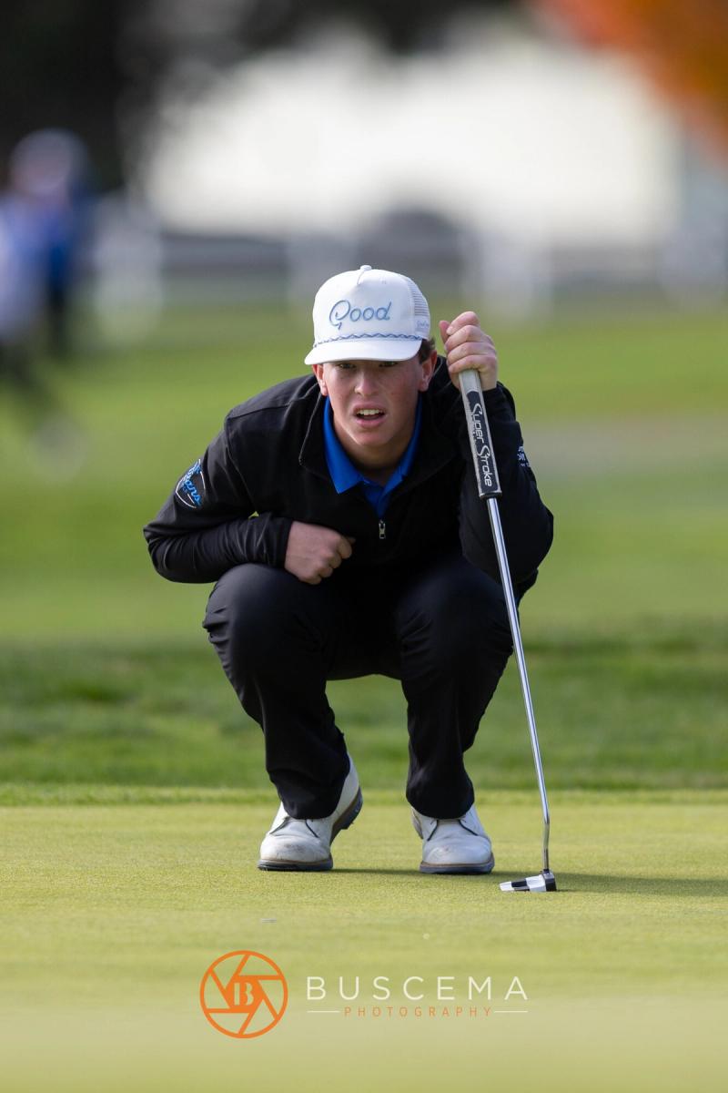 Boys golfer crouched reading the green at the 6A state golf championships at Avondale Golf Club