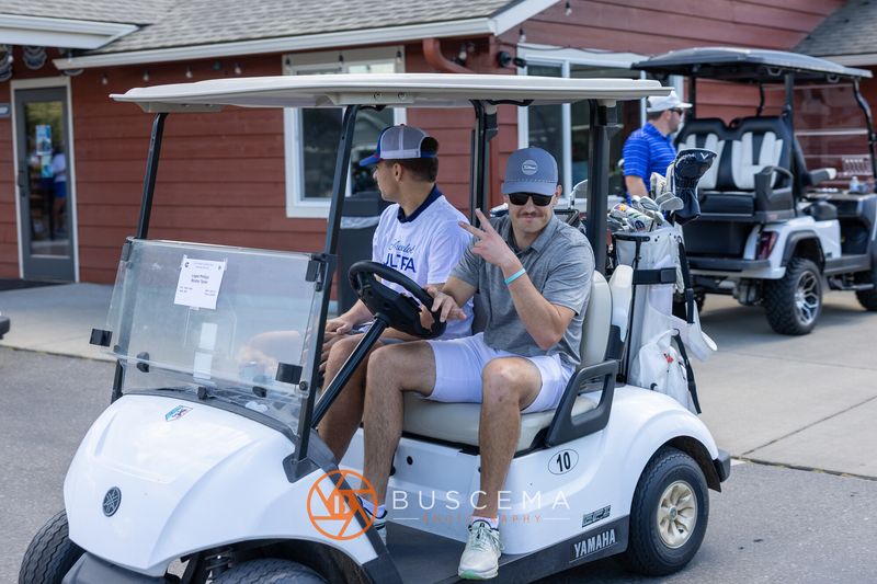 Two golfers in cart 10 giving a peace sign