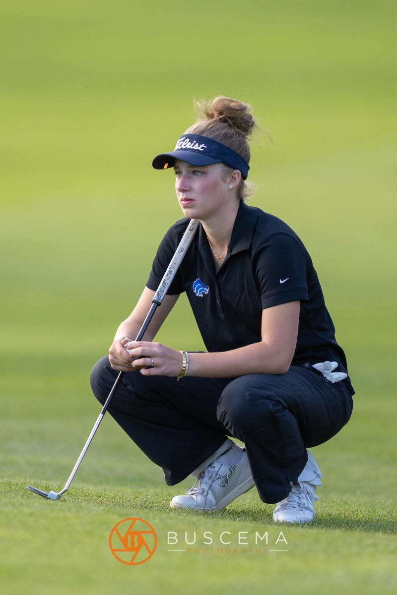 Girls golfer crouched with her putter studying the green at the 6A state golf championships at Avondale Golf Club