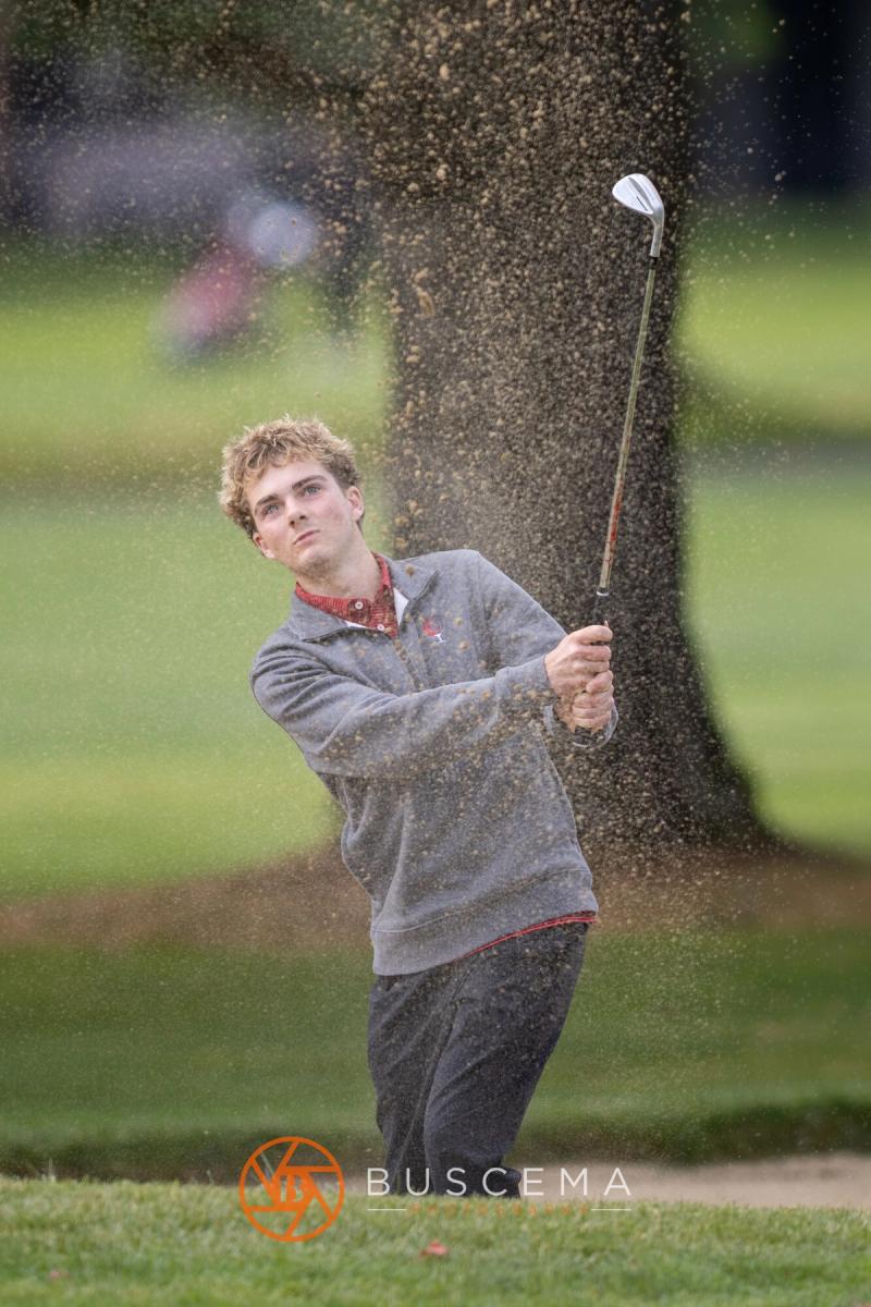 Boys golfer splashing out of a bunker at the 6A state golf championships at Avondale Golf Club