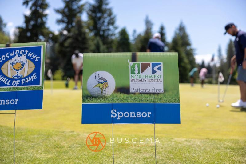 Northwest Specialty Hospital hole sponsor sign with golfers putting behind it