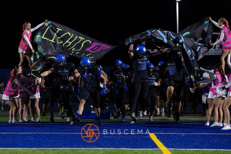 Coeur d'Alene players burst through the team banner as the cheer squad lines the tunnel
