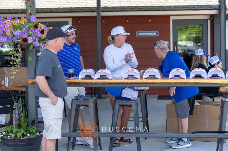 Volunteers handing out Viking Golf Classic hats at the clubhouse check-in