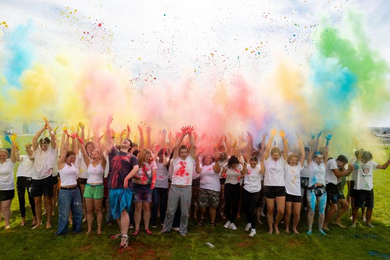 The Coeur d'Alene senior class throwing colored powder into the air on the practice field
