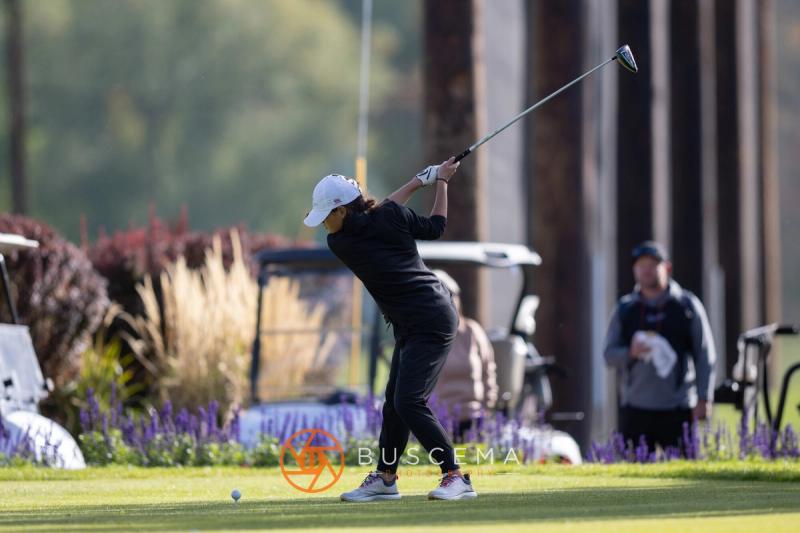 Girls golfer swinging on the tee with purple flowers in front at the 6A state golf championships at Avondale Golf Club