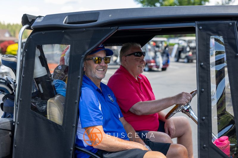 Two golfers smiling from an enclosed cart