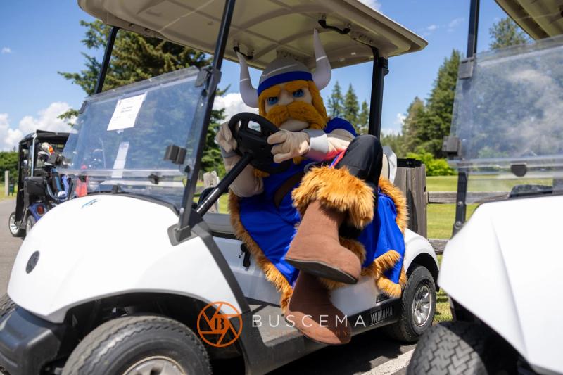 The Viking mascot climbing into the driver's seat of a golf cart