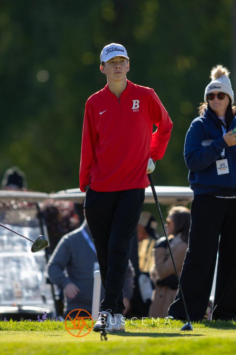 Golfer in a red jacket watching his tee shot fly at the 6A state golf championships at Avondale Golf Club