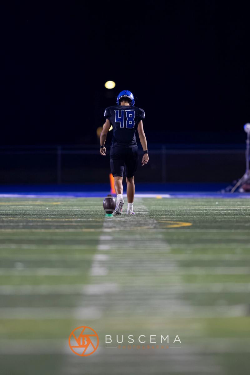 A lone Coeur d'Alene kicker standing over the ball at night