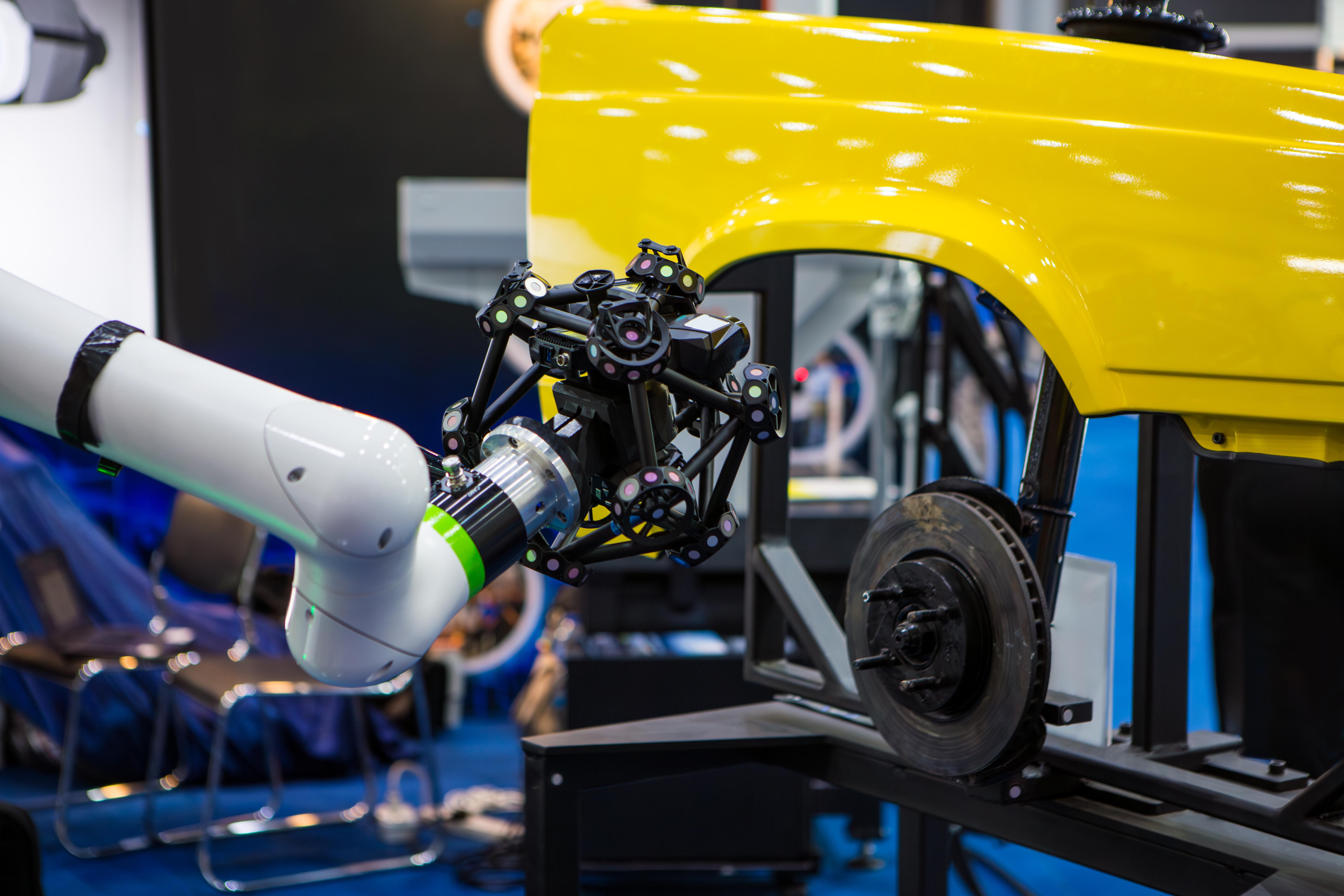 An image of a robotic arm with cameras inspecting automotive parts in a manufacturing facility