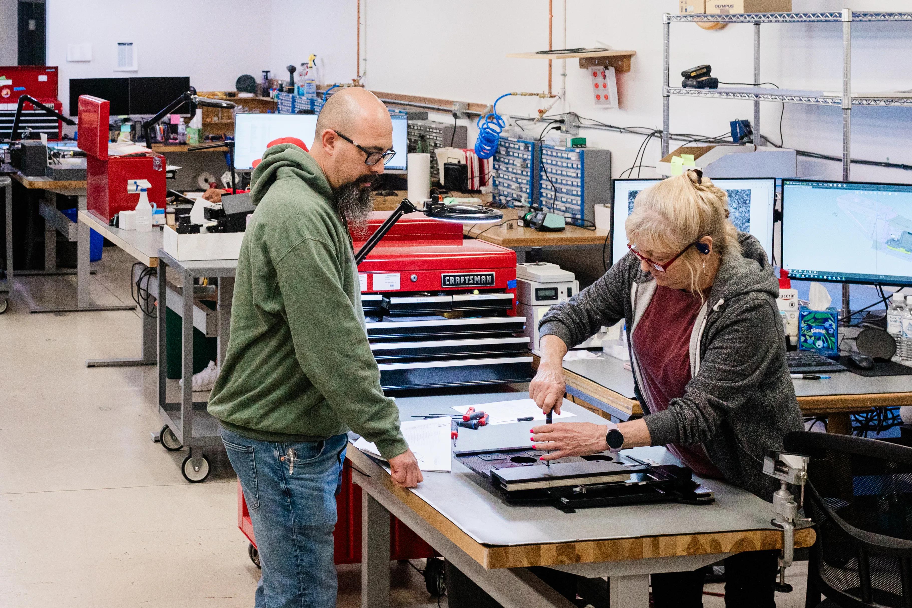 Male and female employees manually assembling a precision inspection tool