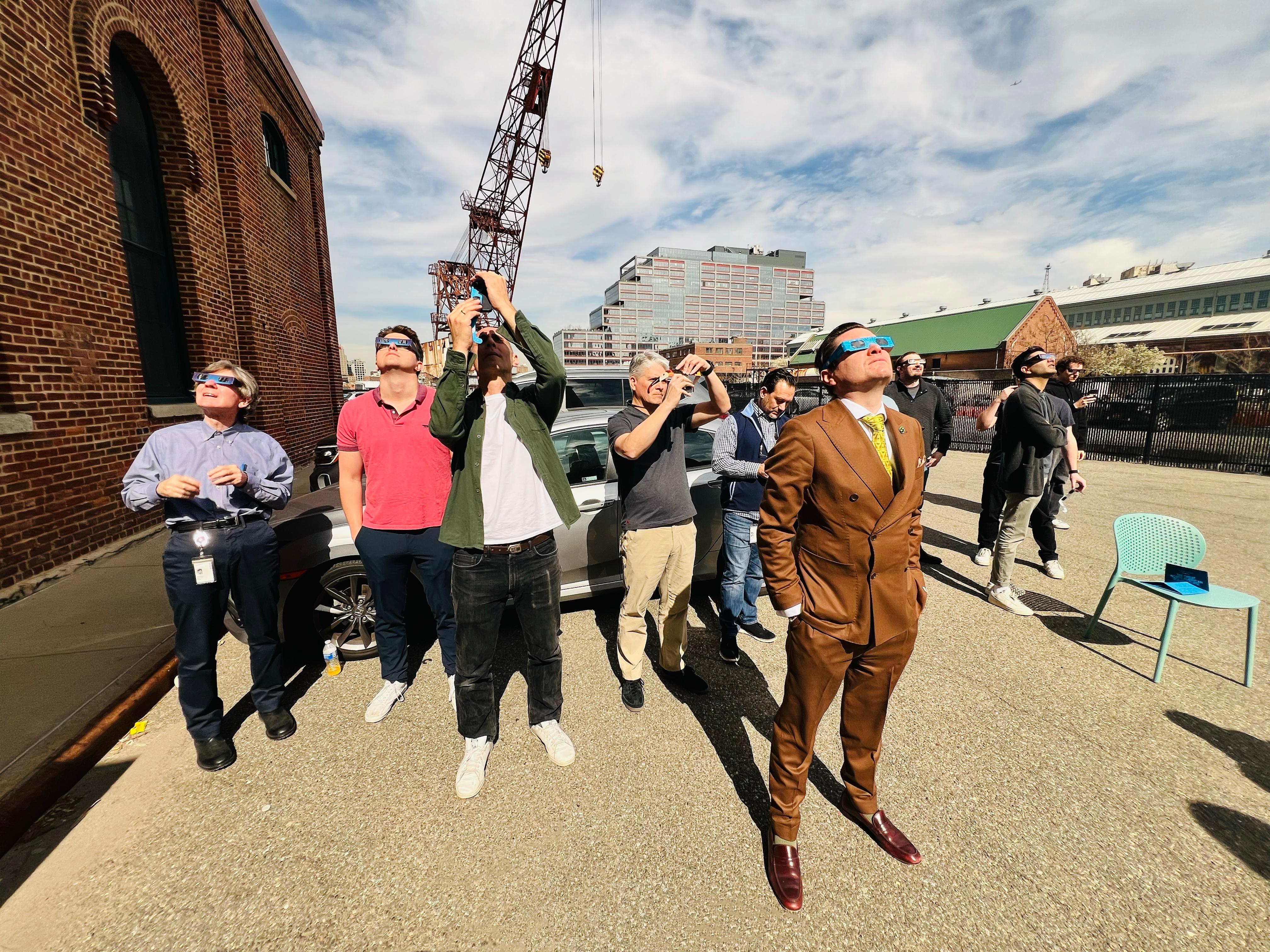 Employees wearing eclipse glasses looking up at the sky