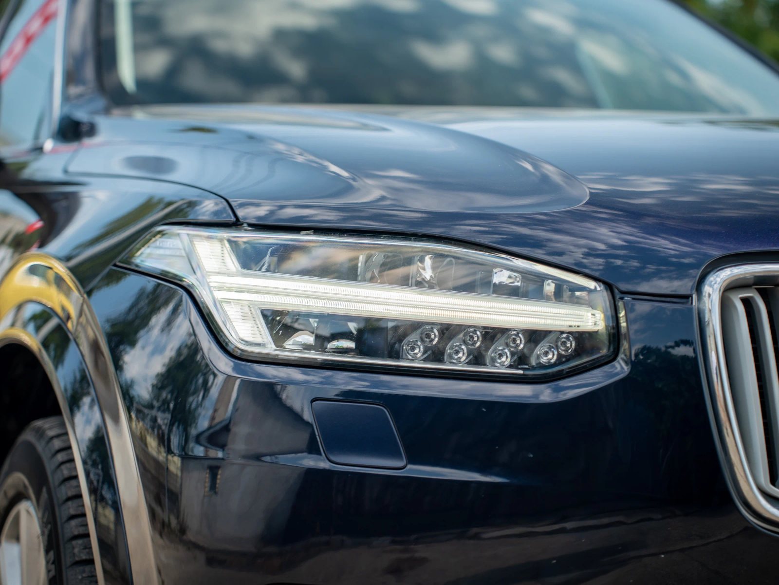 Volvo XC90 — prim-plan al farului și caroseriei.