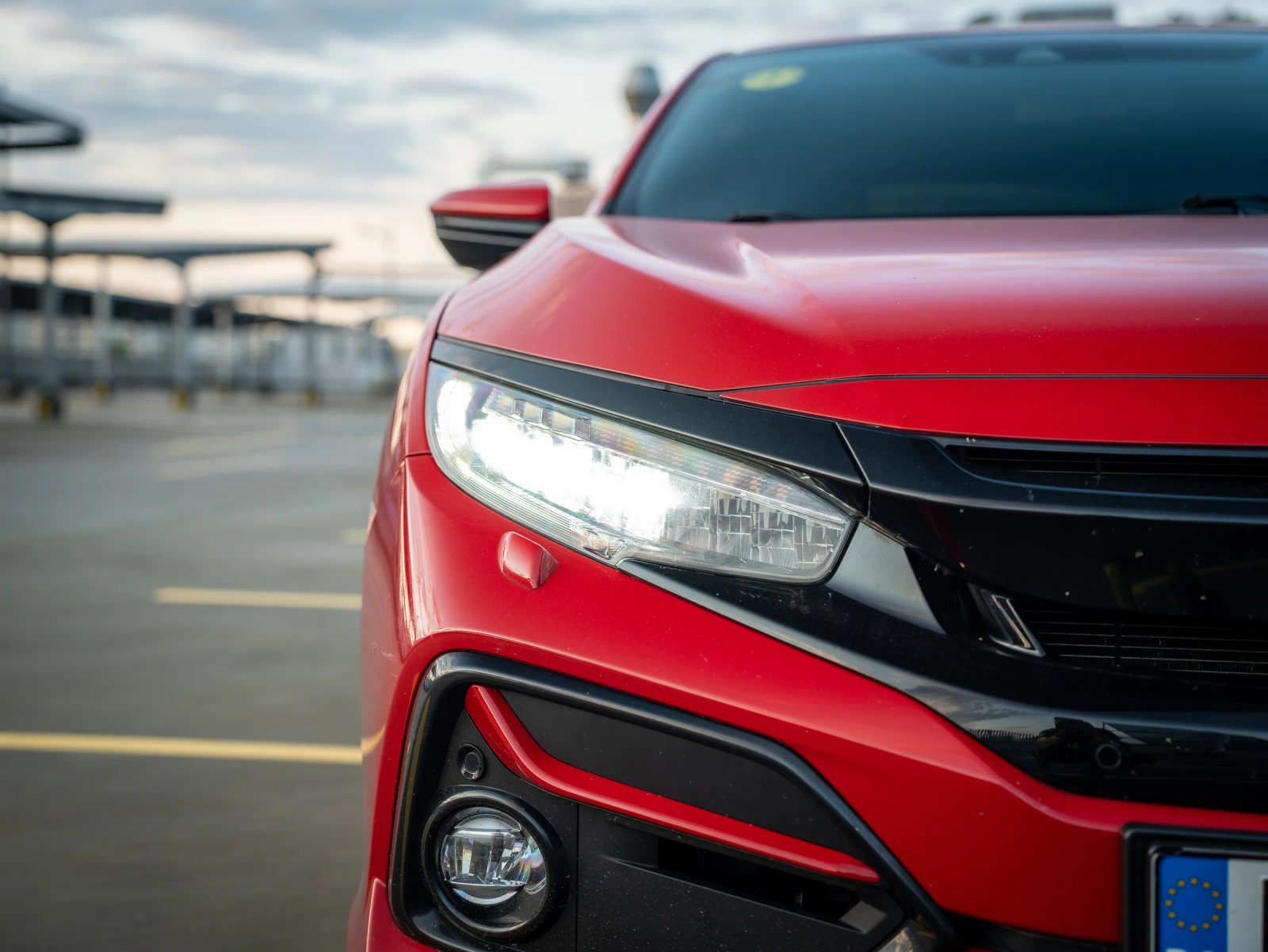 Honda Civic — prim-plan al farului și caroseriei.