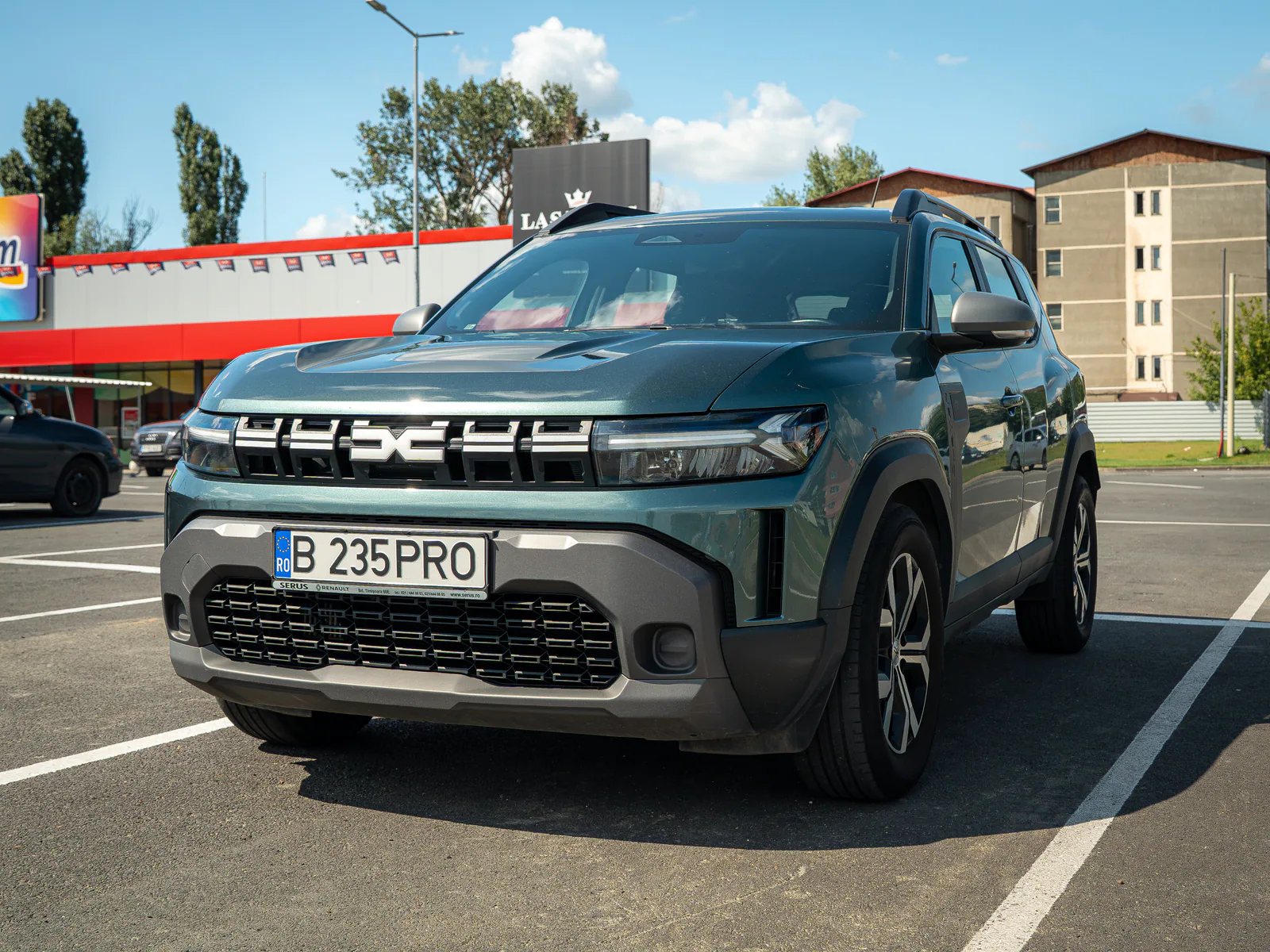 Green Dacia Duster photographed from the front in an urban Bucharest car park