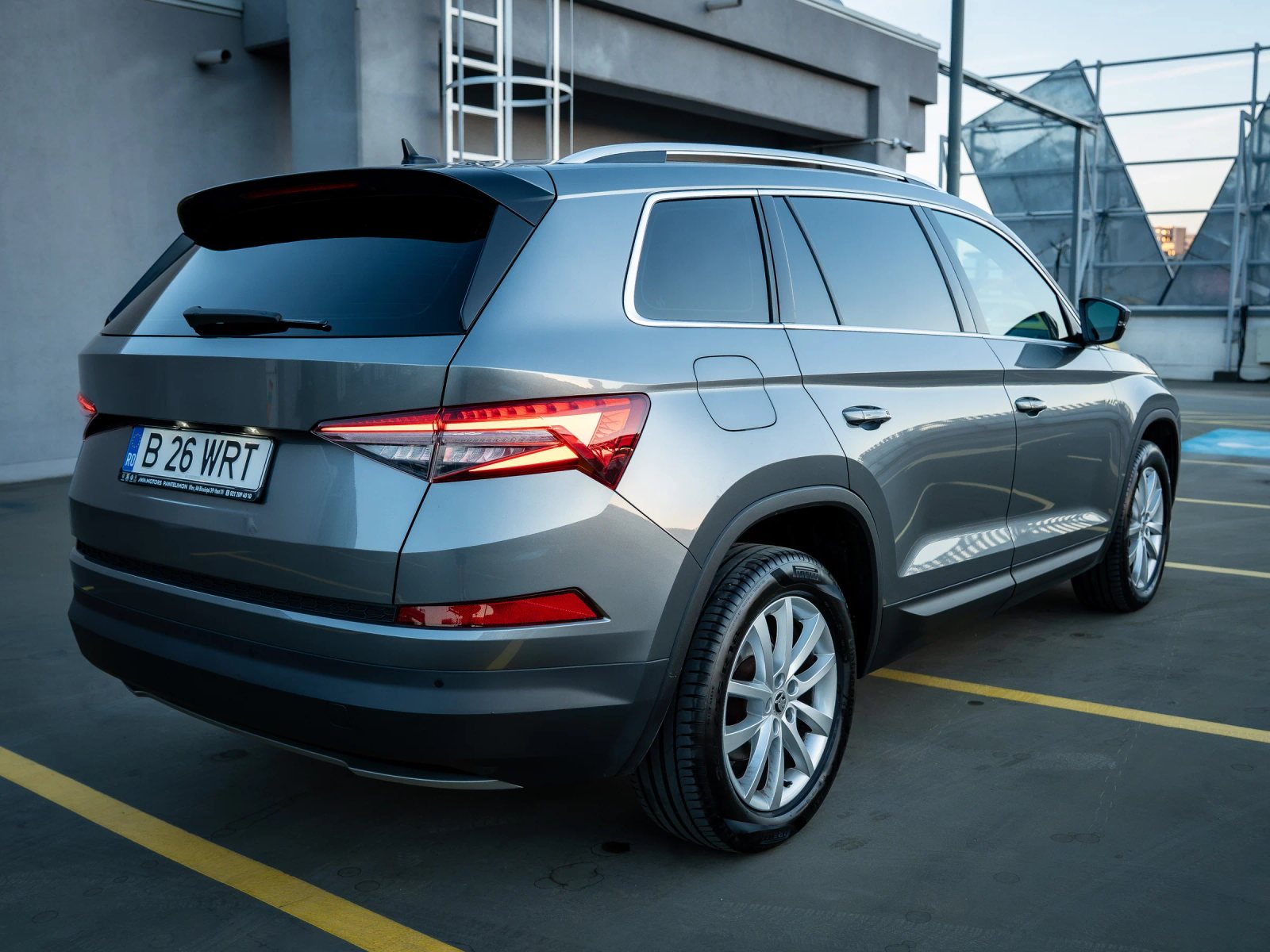 Škoda Kodiaq gri, vedere spate trei sferturi din dreapta, cu stopurile și profilul lateral.