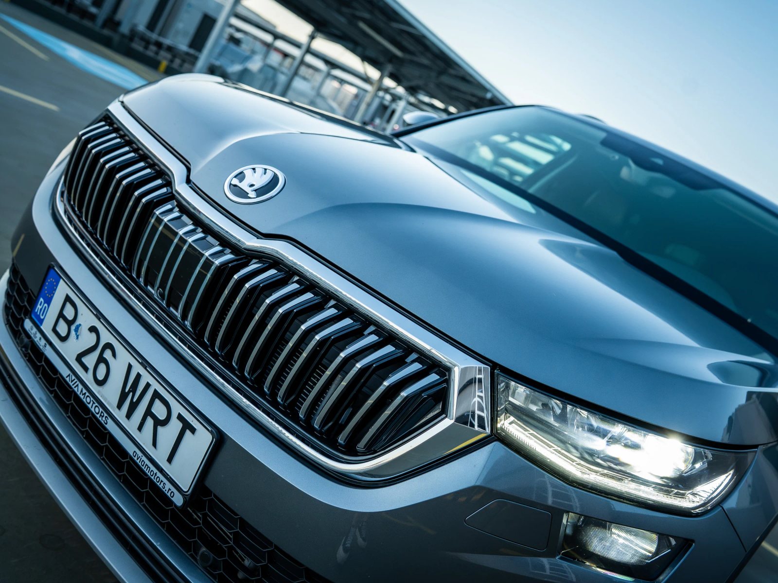 Škoda Kodiaq gri, detaliu înclinat al grilei frontale și al farului.