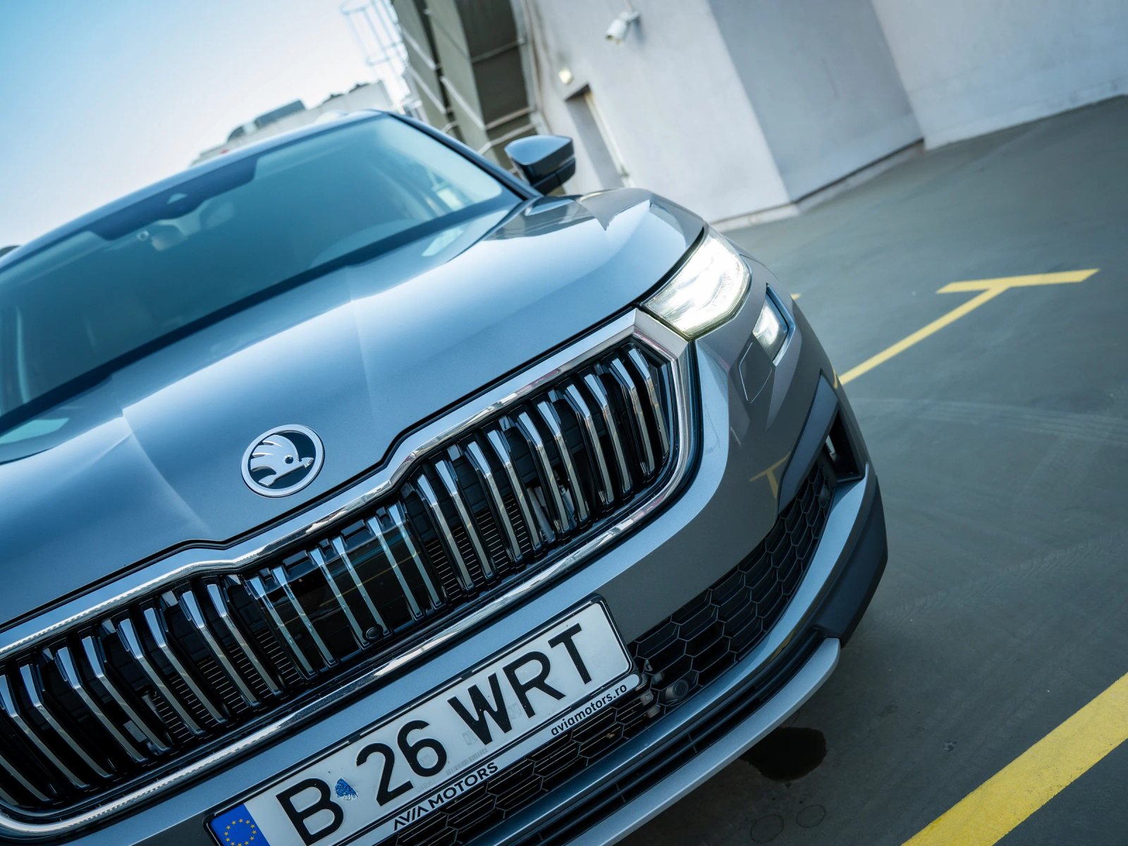 Škoda Kodiaq gri, prim-plan exterior înclinat cu grila și farul în cadru.