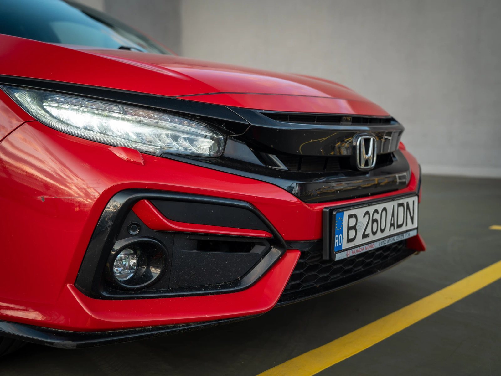 Honda Civic — prim-plan al farului și caroseriei.