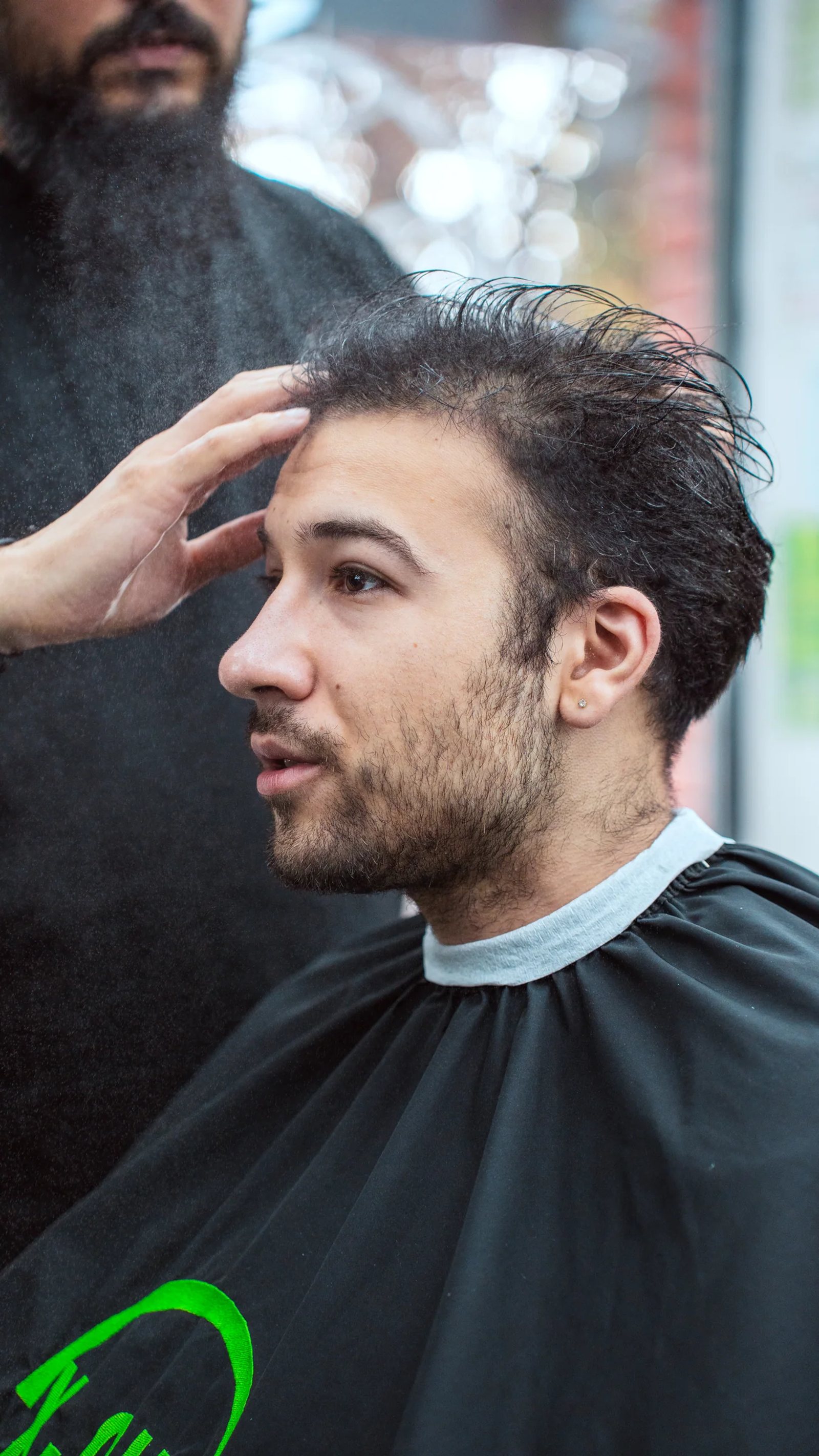 Clientul privește în lateral în timpul pregătirii tunsorii
