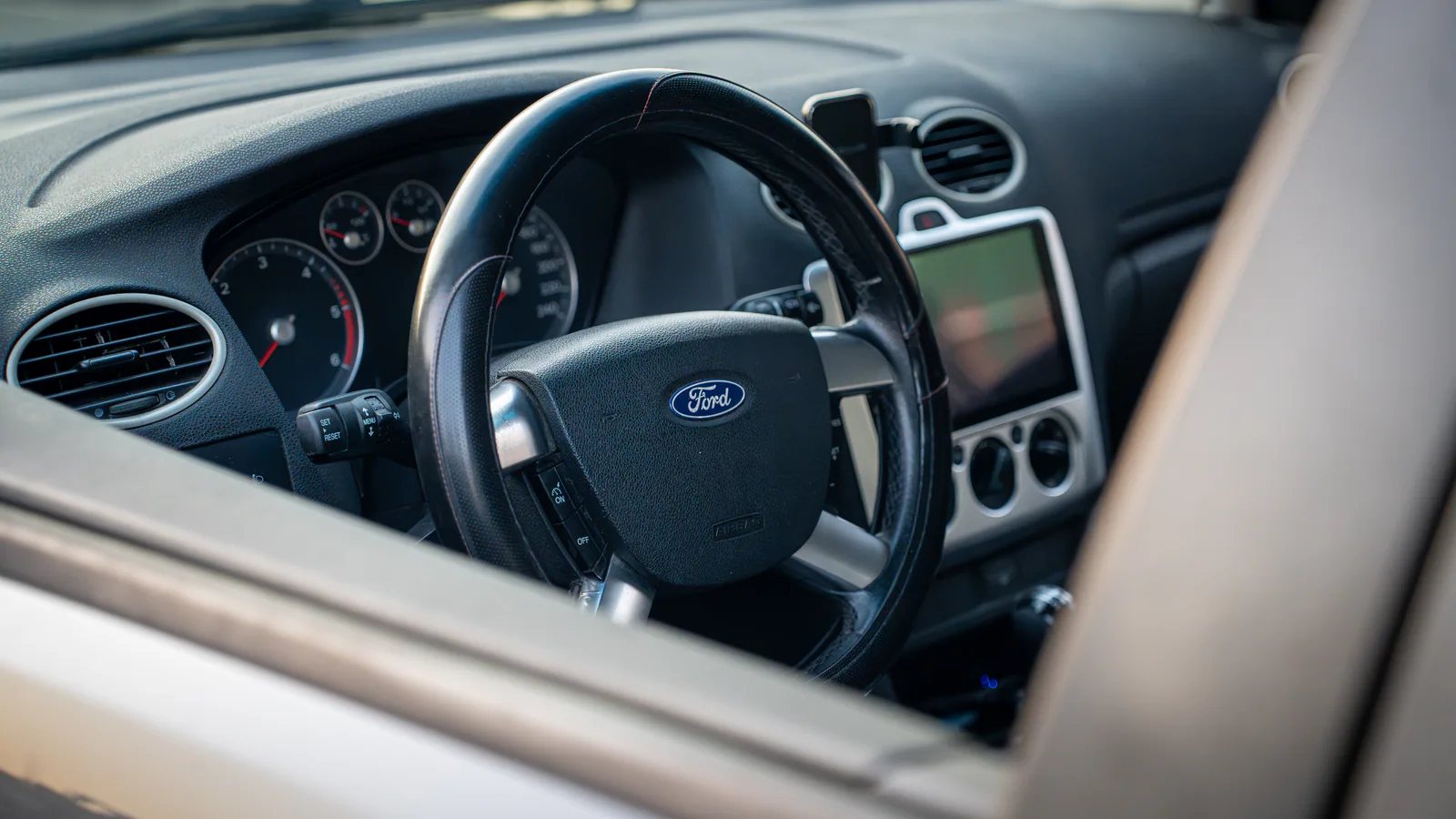 Interior Ford Focus fotografiat prin geamul șoferului, cu volanul și consola centrală în prim-plan