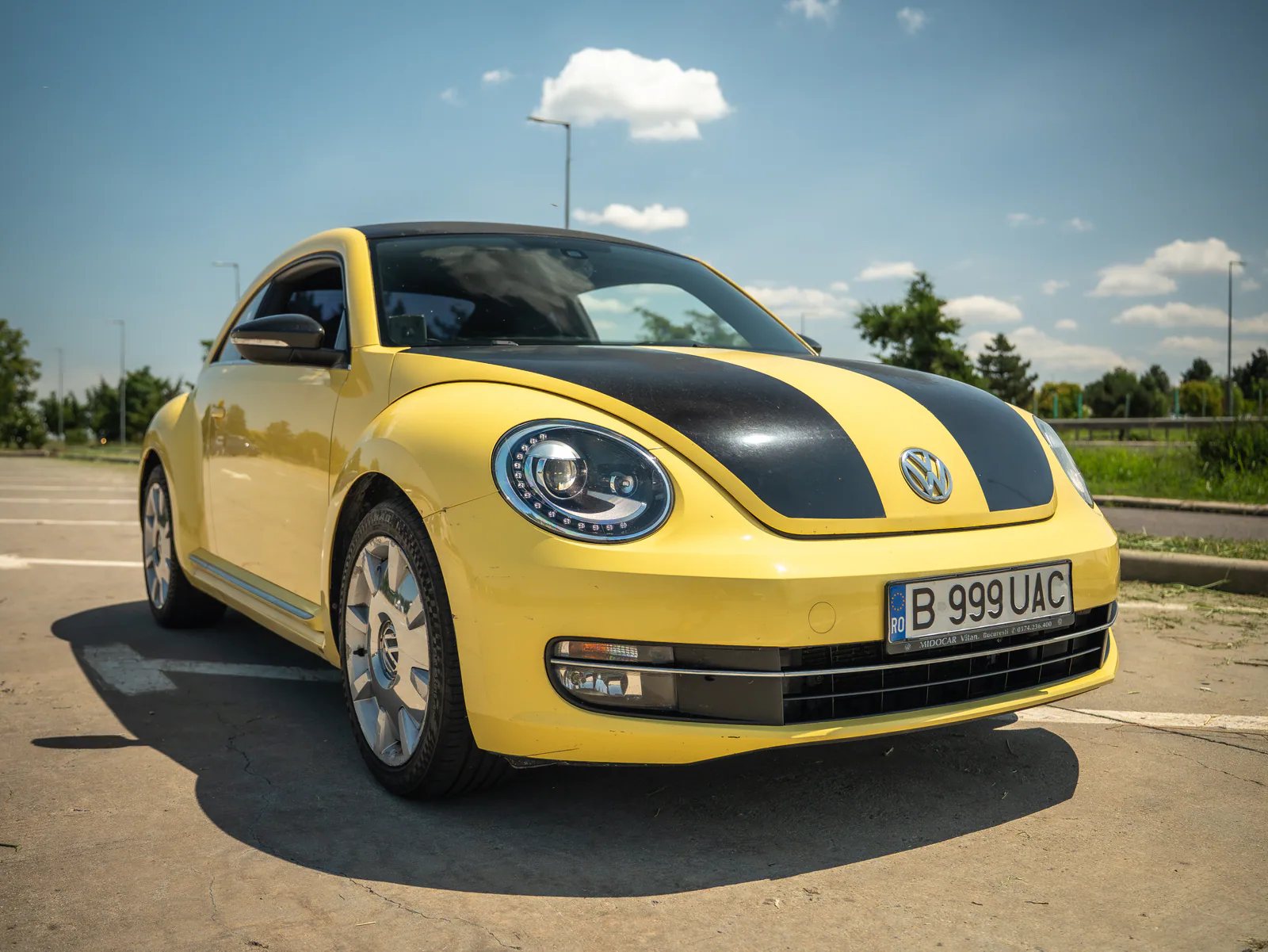 Volkswagen Beetle galben cu dungi negre, fotografiat din față într-o parcare din București