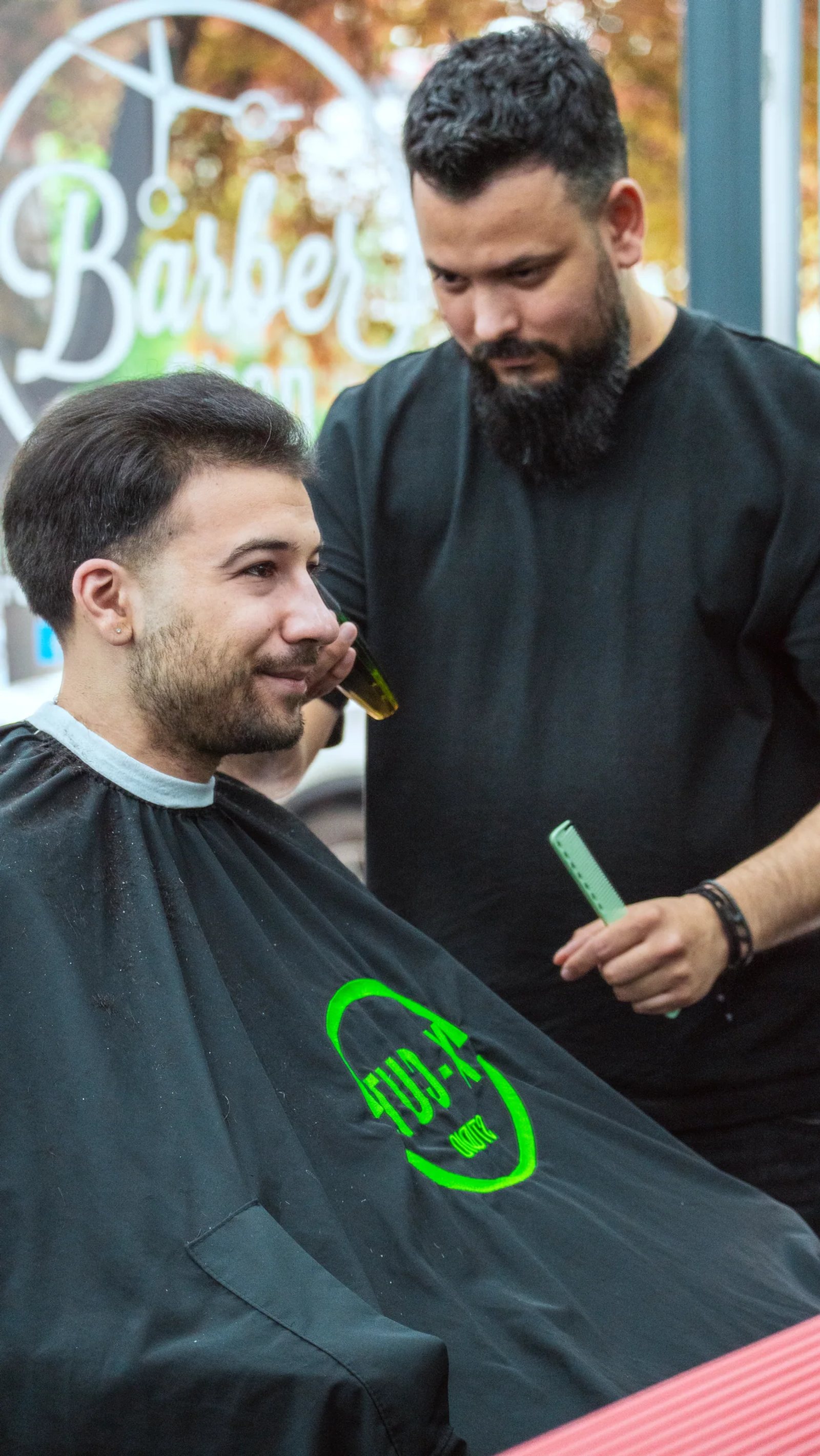 Frizerul discută cu un client așezat în scaunul de tuns