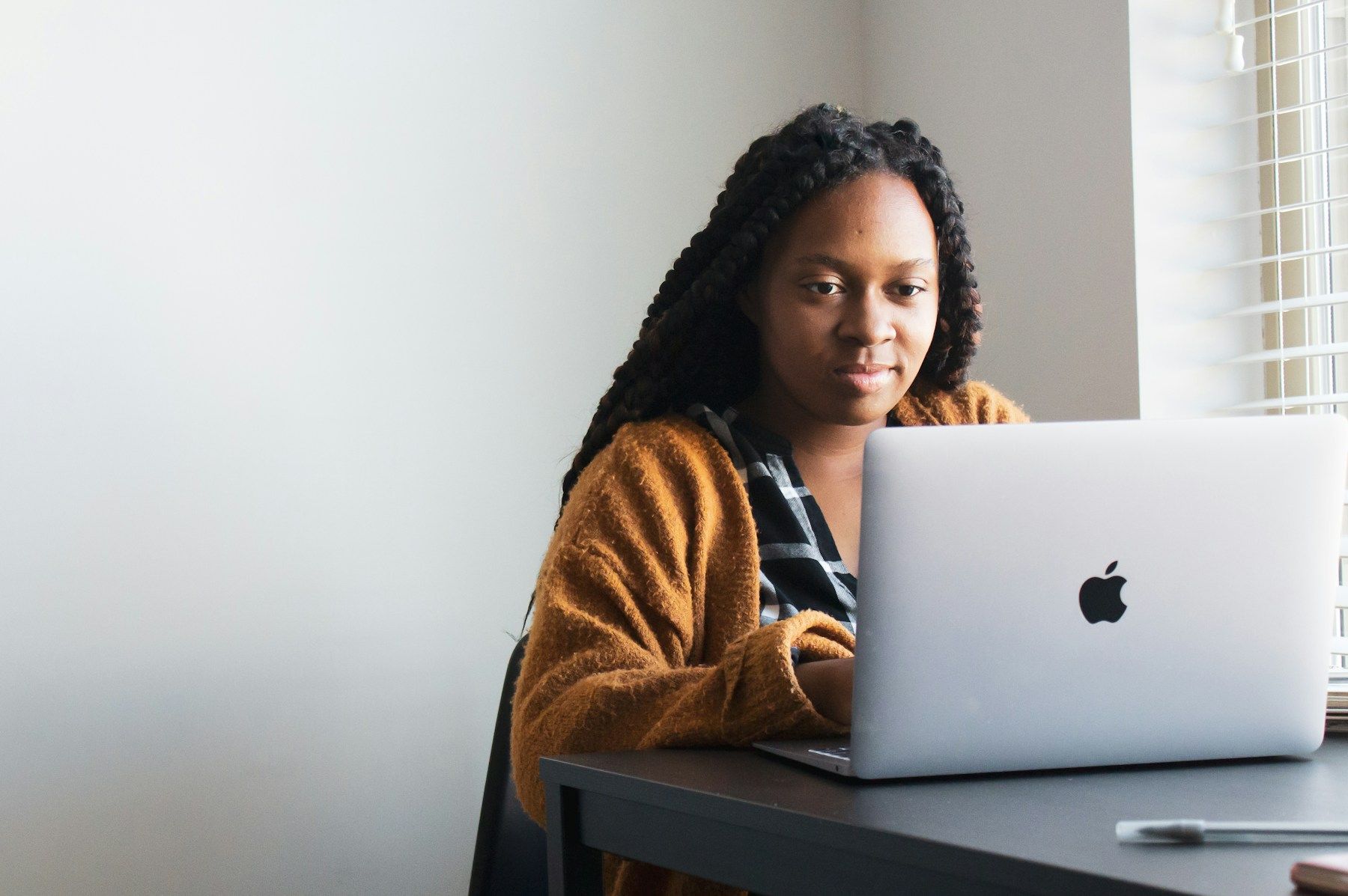 A young woman with braids working on a laptop