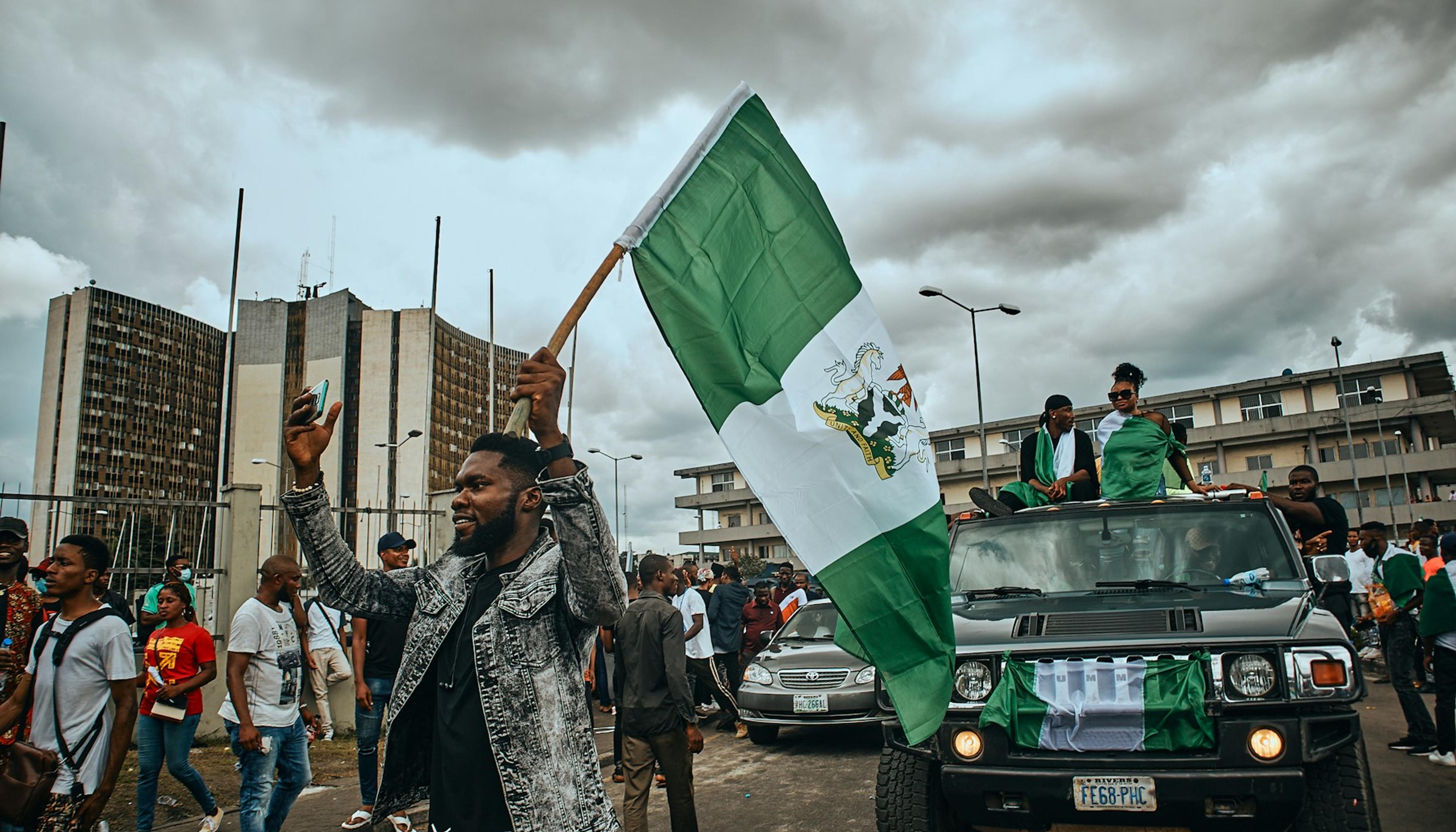 Young Nigerians walking together holding the Nigerian flag