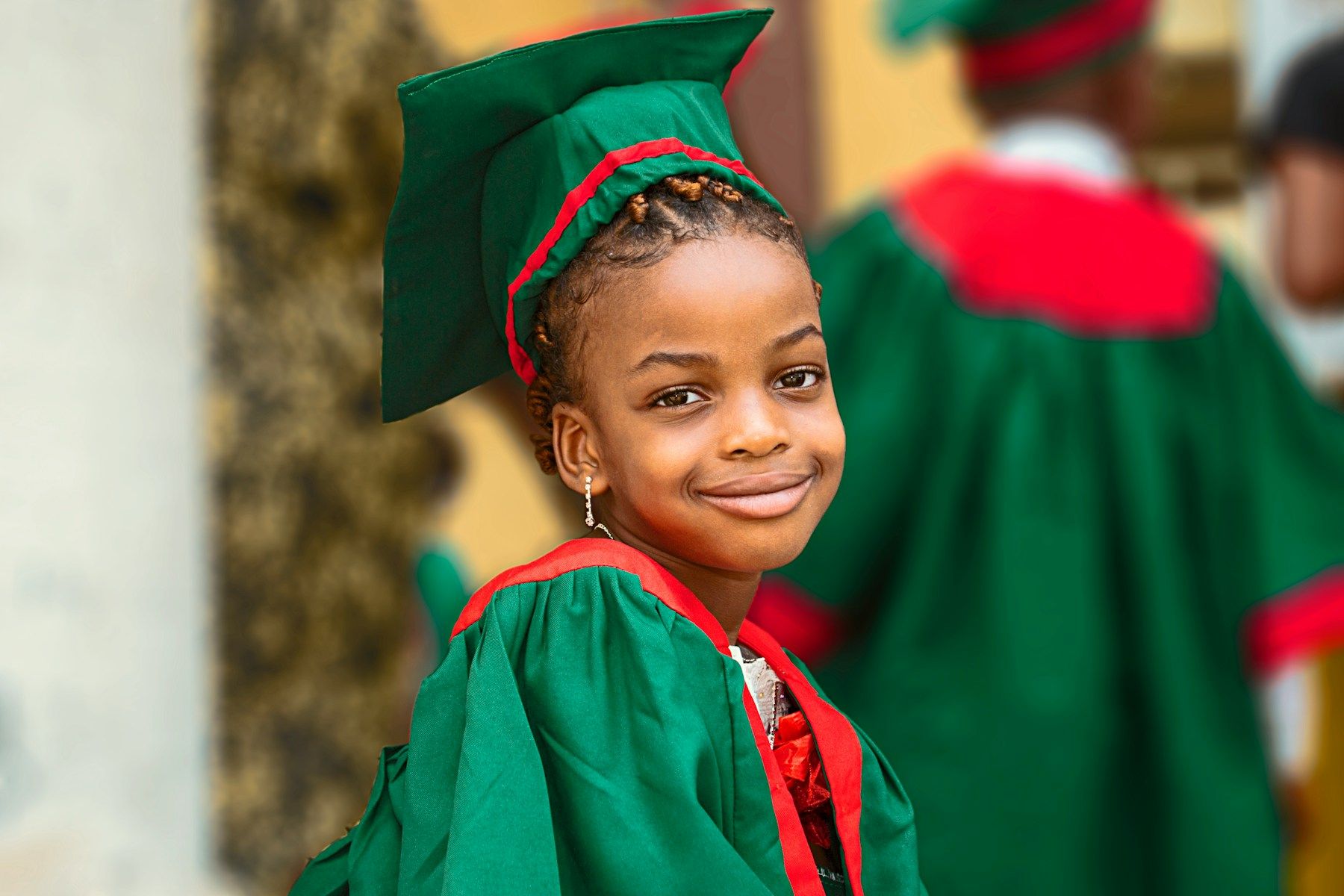 A smiling graduate in a green academic gown