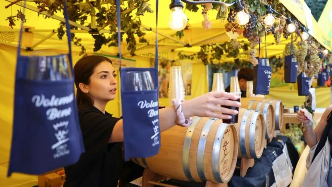 Una venditrice porge un bicchiere di vino a un cliente durante la Sagra dell’Uva di Marino, il 4 ottobre. Foto agenzia Xinhua