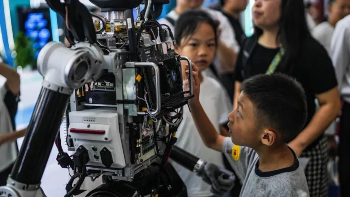 Un bambino osserva la struttura interna di un robot esposto senza rivestimento. Foto Xinhua/Tao Liang
